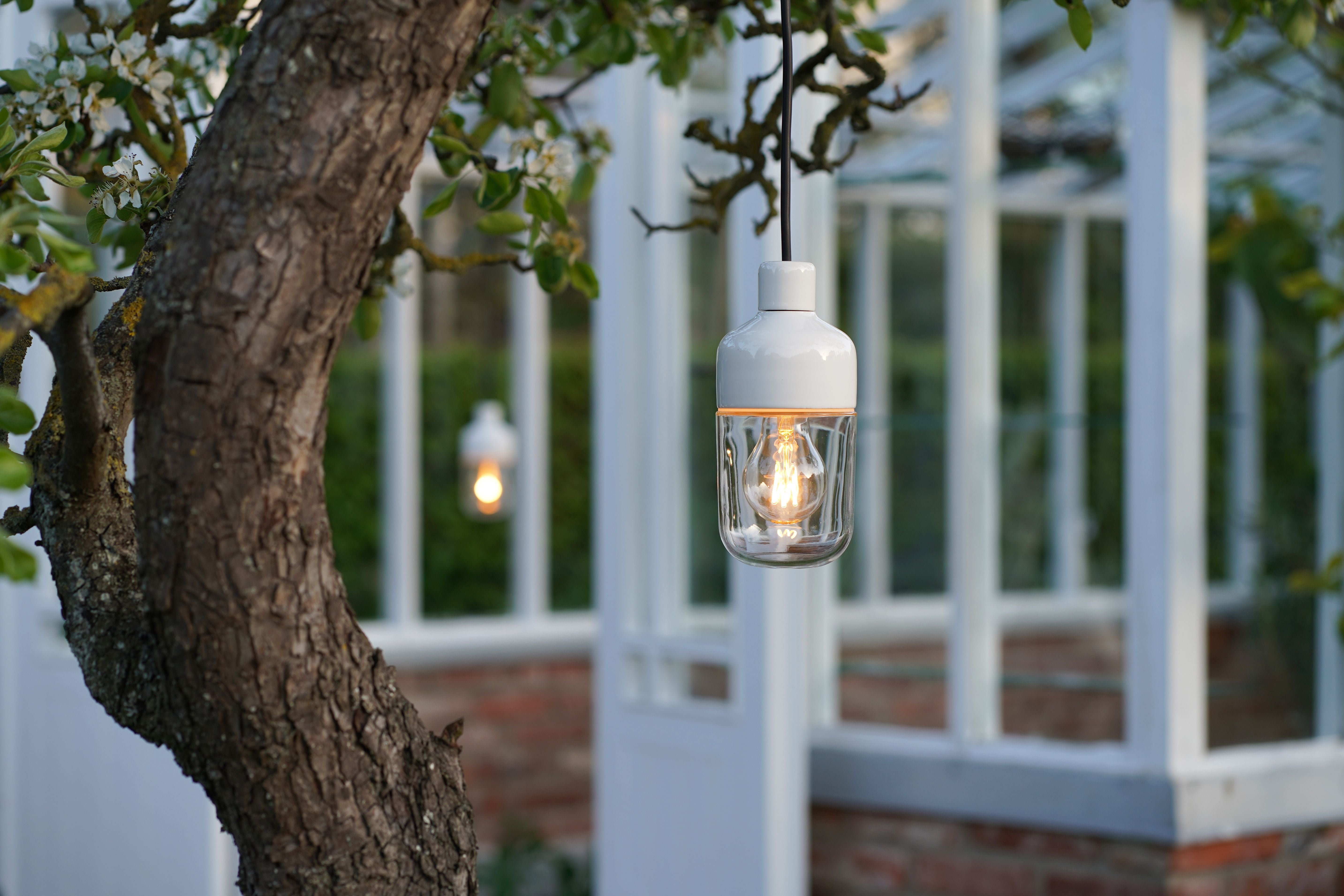 Ohm Pendelleuchte Porzellan 100/215 Outdoor weiss Klarglas, im Garten von Baum hängend | Ifö Electric